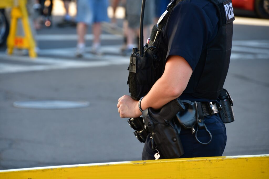 Female Police Officer Standing Guard Behind A Barricade. Police Officers, Law Enforcement